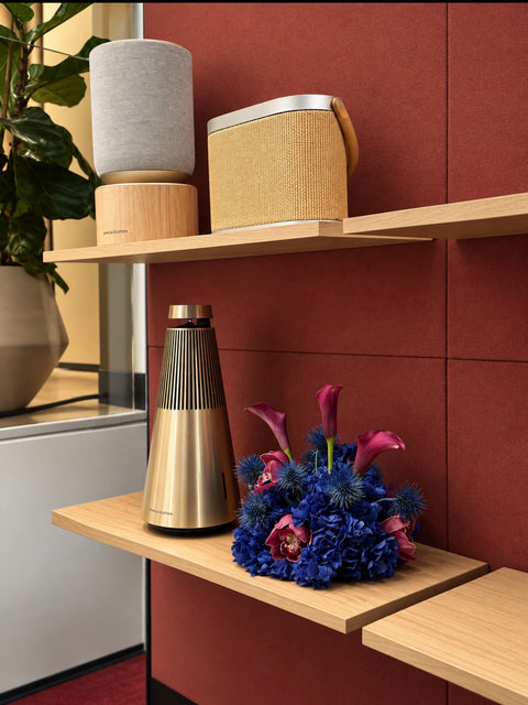 Bang & olufsons Sydney store. The shelves display a stack of speakers and a metallic gold cone-shaped device, alongside a vibrant blue and burgundy floral arrangement featuring calla lilies, hydrangea, orchids and sea holly