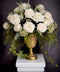 Floral arrangement with white roses and greenery in a gold urn