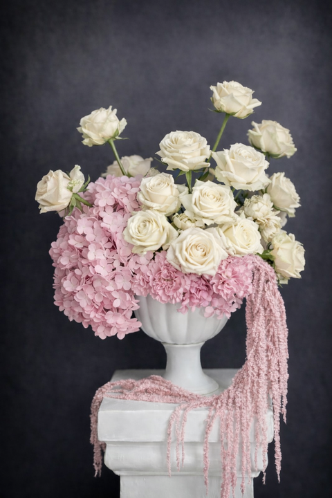 Floral arrangement with white and pink flowers in a vase on a dark background