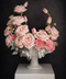 Floral arrangement with pink roses and tulips in a white vase on a dark background