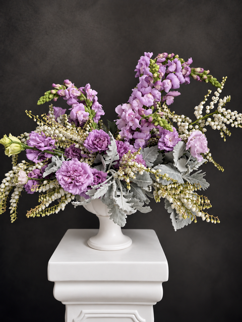 Purple and grey flower arrangement in white vase including lilac Lisianthus and lilac snapdragons 