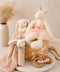 Children's toys including a plush unicorn and bunnies on a neutral background