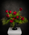 Luxury red rose arrangement with flowing green foliage in a matte black pedestal vase against a dark background