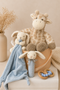 Children's toys including a plush giraffe, bunny, and baby comfort blanket in a bucket on a light surface.