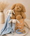Stuffed baby toys hamper including a teddy bear, bunny, and blue comfort blanket on a beige surface.