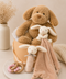 Stuffed dog, rabbit, and blanket in a hamper with decorative elements on a neutral background
