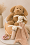 Stuffed dog, rabbit, and blanket in a hamper with decorative elements on a neutral background