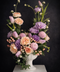 delicate peach garden roses paired with lilac-toned blooms and soft pink tulips in white vase on dark background