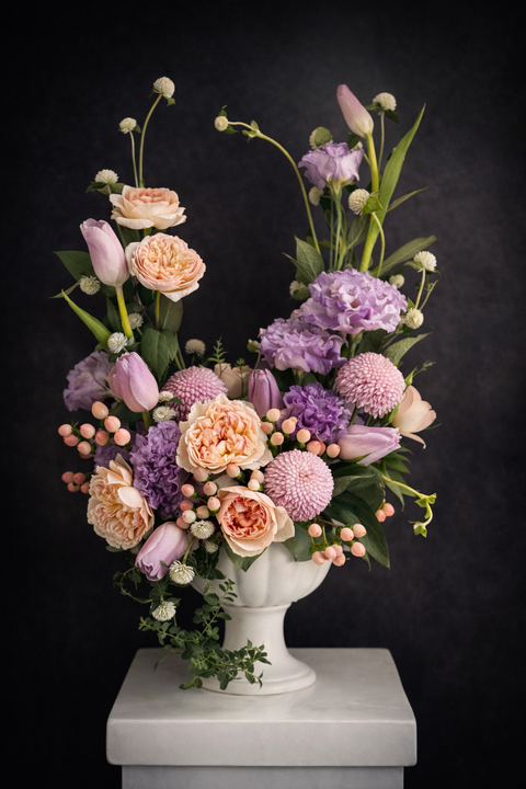 delicate peach garden roses paired with lilac-toned blooms and soft pink tulips in white vase on dark background