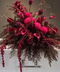 A dramatic Funeral Casket flower Cover in deep burgundy, magenta, and dark brown foliage, styled over a white bathtub with chrome faucets against a warm gray-brown background.