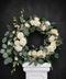 Floral wreath with white flowers including roses, lisianthus, orchids and eucalyptus leaves 