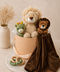 Two lion plush toys with a baby blanket and small dinosaur rattle toy in a hamper including teething ring