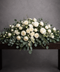White flower casket cover for funeral with roses, carnations, orchids, eucalyptus and snapdragons